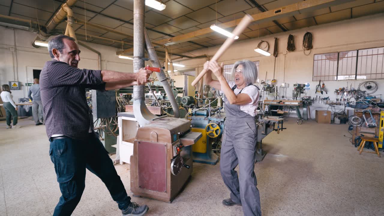 Man and Woman Playfully Dueling with Props in a Workshop