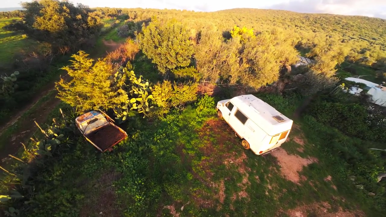 FPV droneflyvning gennem landlige omgivelser med forladt køretøj og skur, 4K.