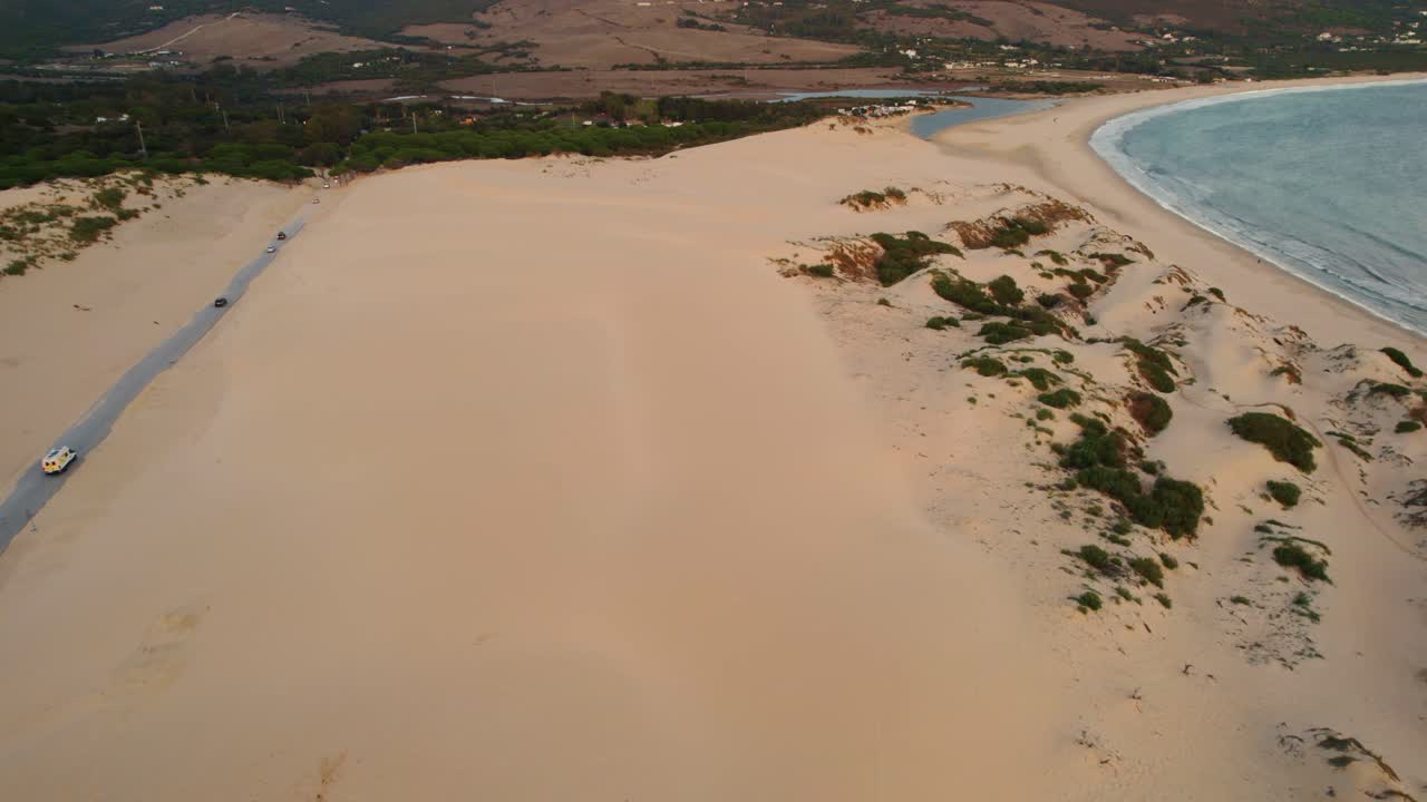 vista aérea de una amplia playa de arena en tarifa, españa con coches circulando por la carretera cercana