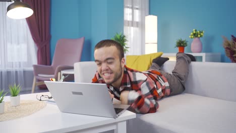 joven enano discapacitado feliz y alegre usando una computadora portátil, acostado en el sofá y descansando.