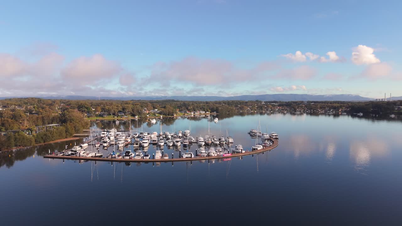 Aerial panoramic establishing of Trinity Point waterfront and marina with boats docked, calm reflective ocean waters