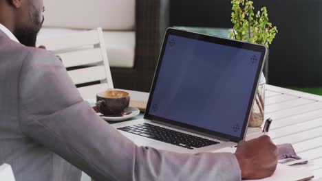 Midsection-of-african-american-businessman-using-laptop-in-cafe