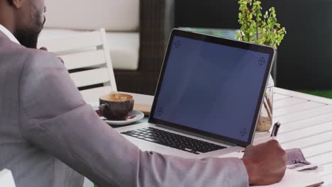 sección media de un hombre de negocios afroamericano usando una computadora portátil en un café