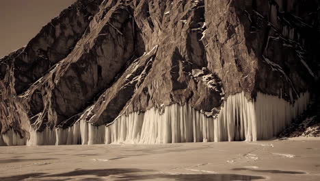 a majestic mountain face adorned with an impressive array of long icicles over a frozen landscape