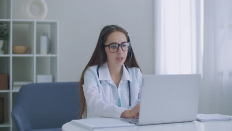 Hardworking-Indian-Female-Doctor-doing-Video-Call-on-Laptop-in-hospital.-Smiling-young-female-doctor-wear-white-uniform-stethoscope-consulting-online-patient-via-video-call