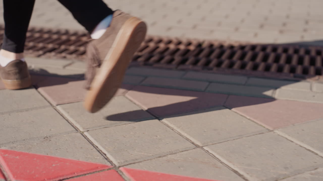 Casual sneakers traversing city. Shoes crossing red line with confident stride amid urban environment. Closeup of casual sneakers crossing marked line with purposeful movement and city backdrop