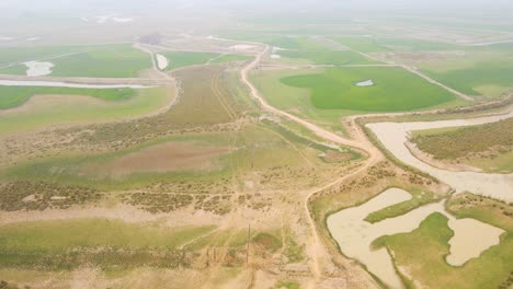 Aerial-view-flying-above-row-of-electrical-power-lines-stretching-across-Asian-agricultural-farmland