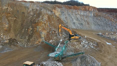 maximizing material output: an aerial shot of a tracked incline screener, excavator, and wheel loader in a mining quarry