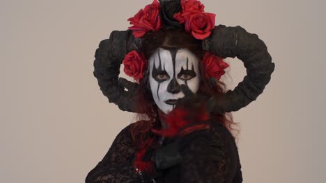catrina cosplay girl with hands crossed on her chess and moving them slowly with a light background, medium close up