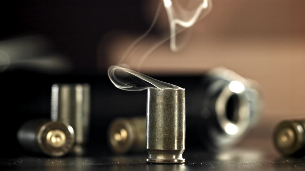 使用済み薬莢から立ち上る煙と背景の銃