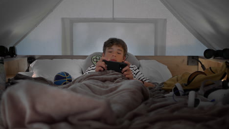 boy playing on smartphone in loft bed