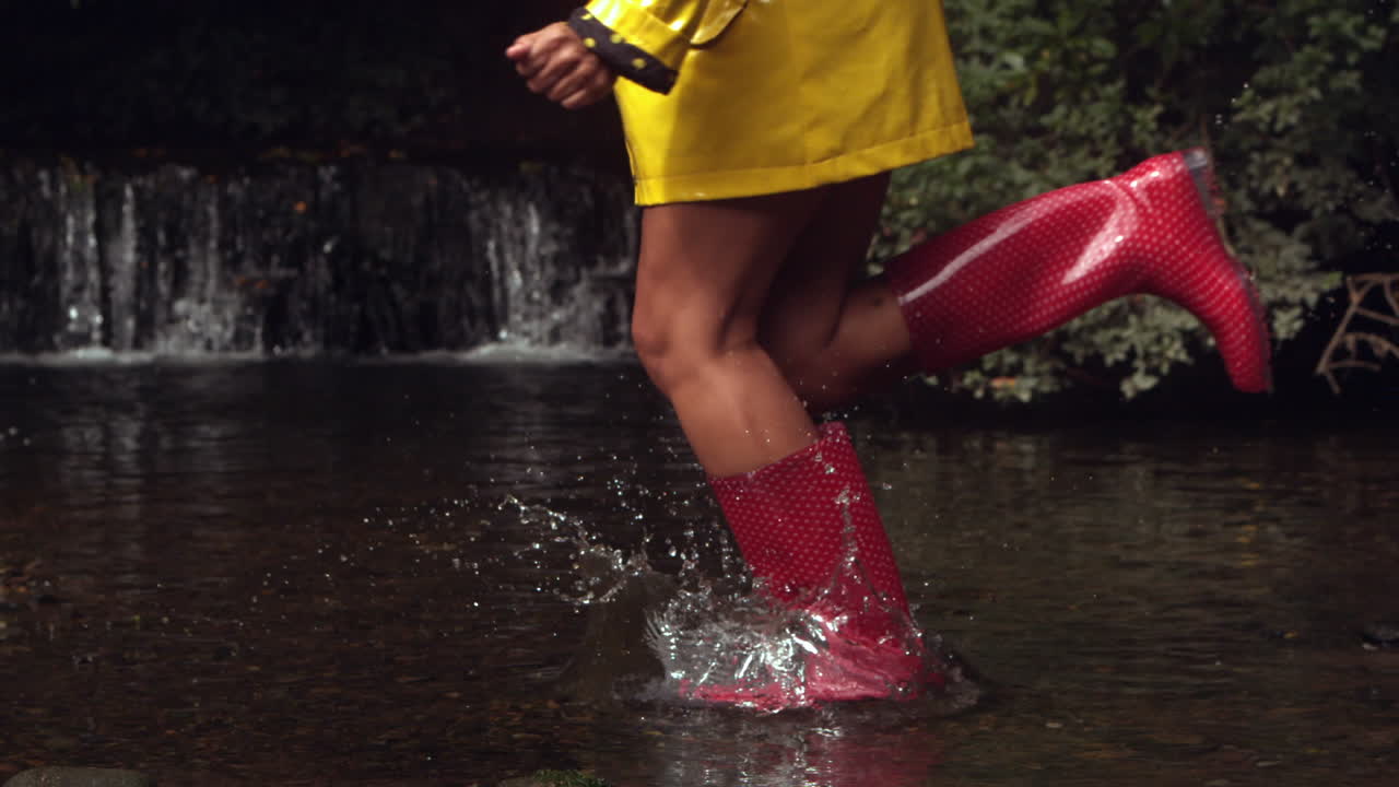 Mujer con botas de goma rosas corriendo en el agua