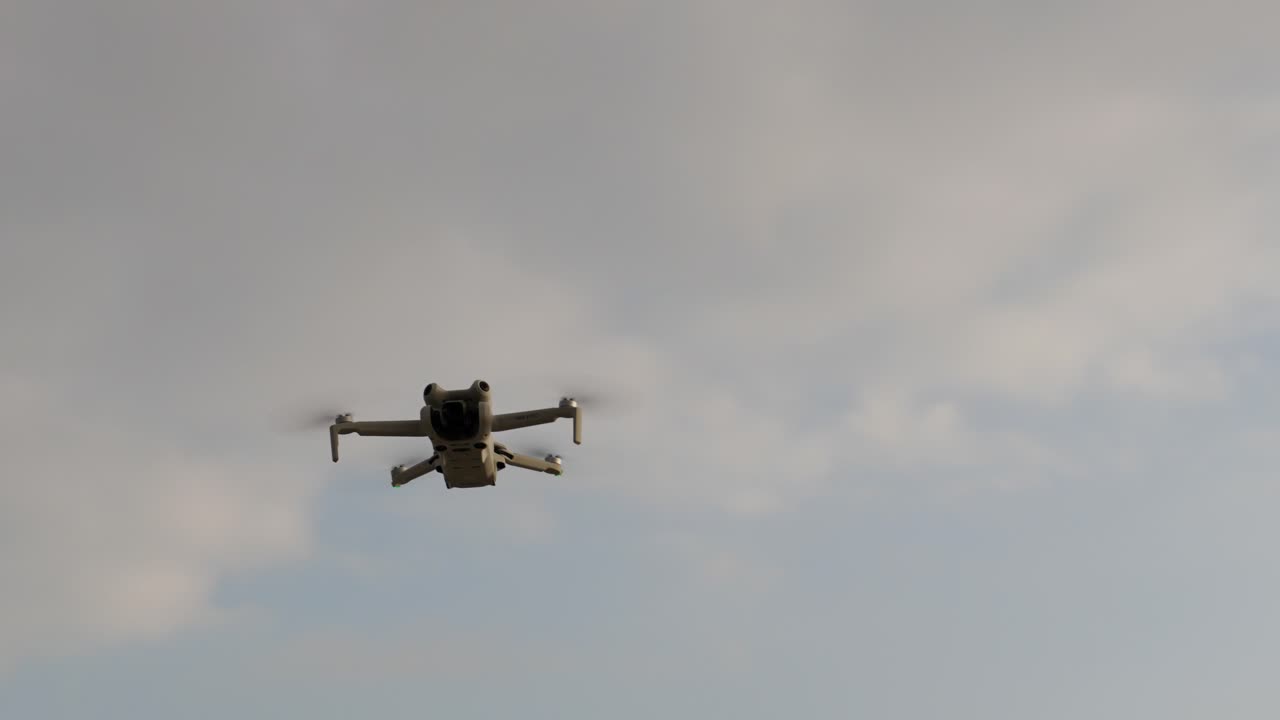 A drone flies smoothly against a cloudy sky