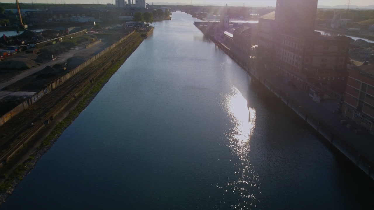beautiful drone footage fying into the setting sun over the River Rhein in Germany with docks and warehouses are in plain sight