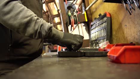 young asian auto mechanic examining engine at car hood in auto repair workshop