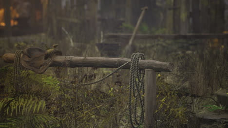 rustic saddle and rope resting on weathered wood in a misty forest setting