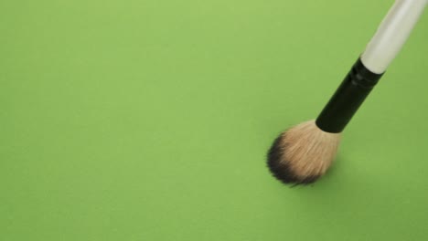 horizontal movement of the brush for makeup on a green background.