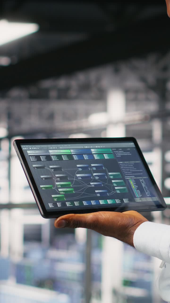 Vertical video Close up of programmer swiping on tablet display in data center, checking code