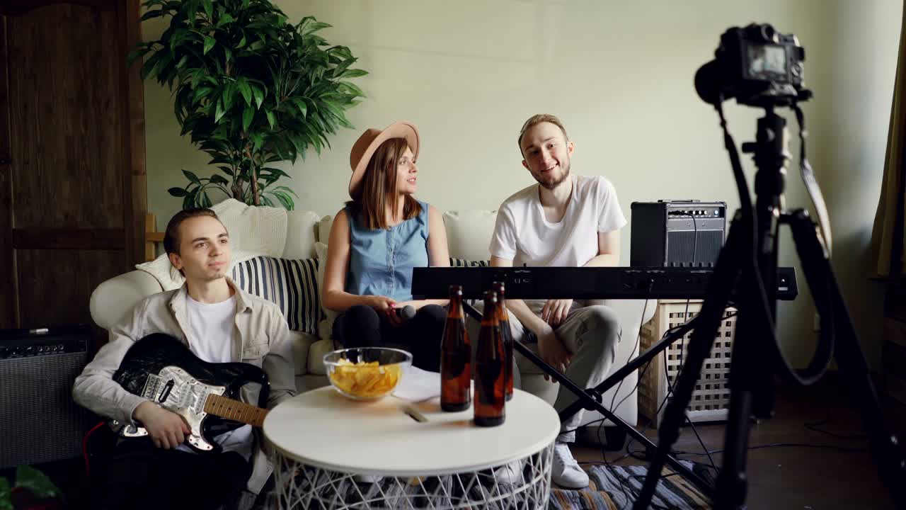 크리에이티브 뮤지션들은 온라인 블로그를 위해 비디오를 녹음하고 있으며, 트라이포드에서 카메라를 보고, 몸짓을 하고, 웃고 있습니다.