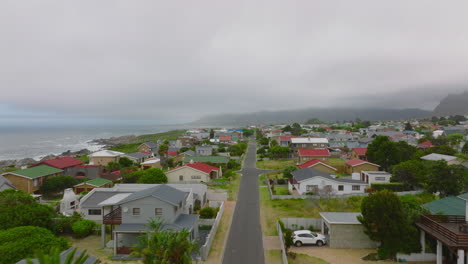 Forwards-fly-above-modern-family-houses-along-straight-street-at-seaside.-Overcast-sky.