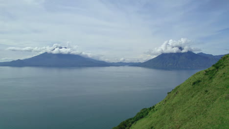 drone aerial footage of guatemalan volcanos volcan de atitlan and volcan san pedro in central american highlands lake atitlan, guatemala surrounded by blue lake water