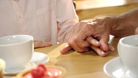 senior couple holding hands on cafe table 4k