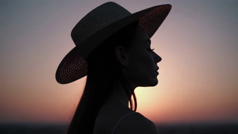 silhouette of a woman wearing a hat at sunset