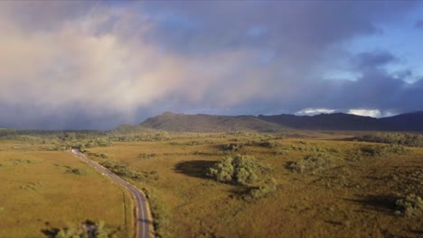 vuelo aéreo sobre montañas nubladas y pastizales en tasmania en australia, tiro de larga distancia avanzando y descendiendo