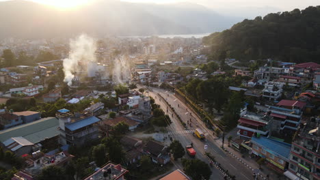 pokhara, nepal - the bustling cityscape, glowing in the sunset, is framed by the majestic himalayas - drone flying forward