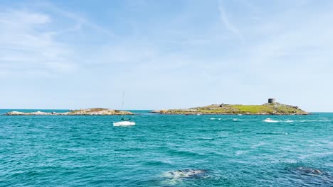 dalkey island with church ruin and martello tower in the distance on a beautiful sunny day. boats slowly coming into the shore