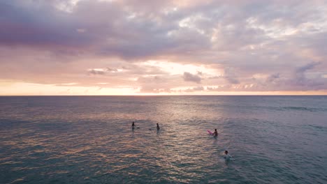surfistas relajándose en las aguas del océano en oahu al atardecer, hawaii, paso elevado