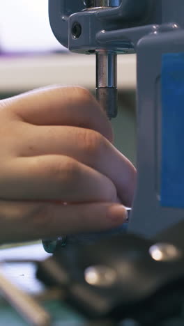 cu: professional tailor changes metal nozzles in special press machine and leather belt on foreground close view