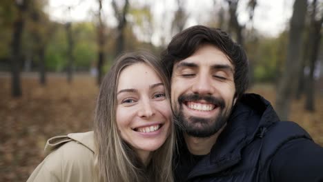 cute couple making selfie on a bench in the park at autumn fall season