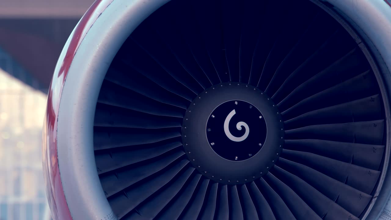 el avión está de pie al lado del edificio del aeropuerto, la turbina roja gira