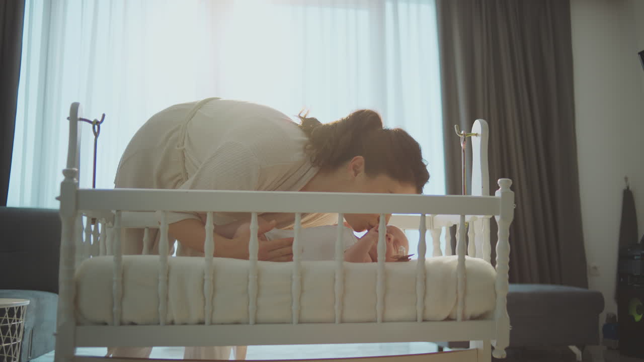 Mother Kissing Baby in Crib