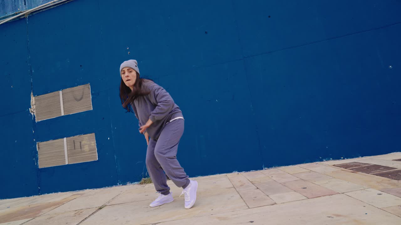 Donna che balla per strada di fronte a un muro blu
