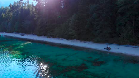 an emerald colored lake with a shady beach, hiding a couple from the harsh sunlight