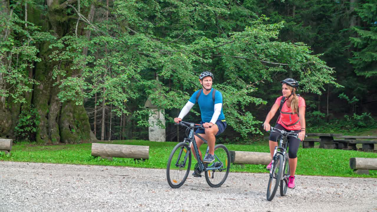 Happy couple cycling pass Najevska Linden Tree a very old Tilia cordata