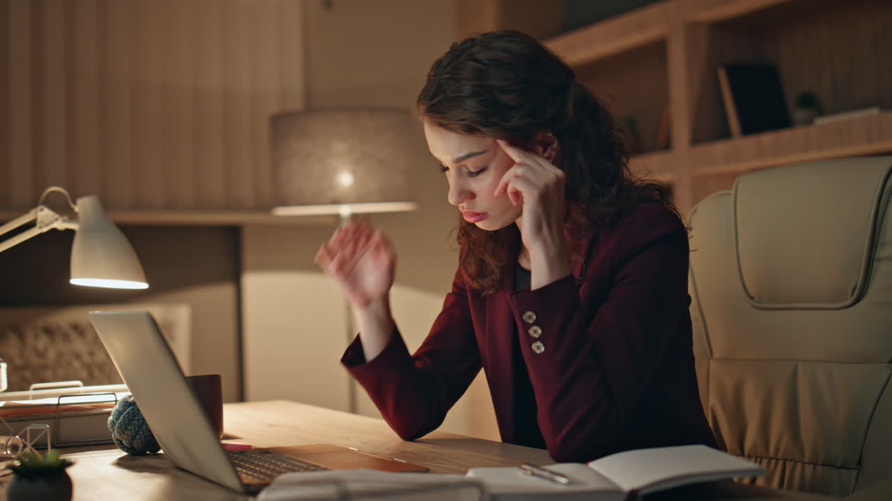 Tired woman looking documents working on laptop late evening office close up.