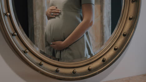 pregnant woman touching belly mirror reflection