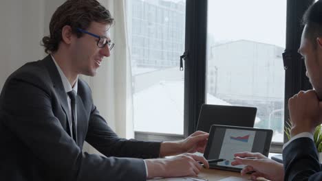 the manager is presenting the company's earnings through the tablet to the shareholders. business men brainstorming about ways to increase sales for the company.