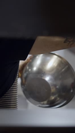 a person with tattooed arms in an apron preparing food in a kitchen