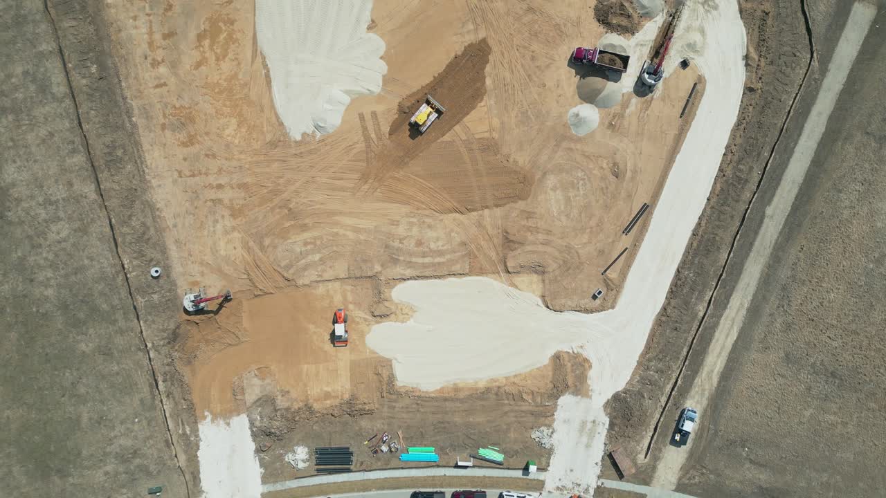 Aerial drone over a working construction site in Ozaukee County, Milwaukee, Wisconsin. Heavy machinery vehicles laying out the groundwork of a new development project