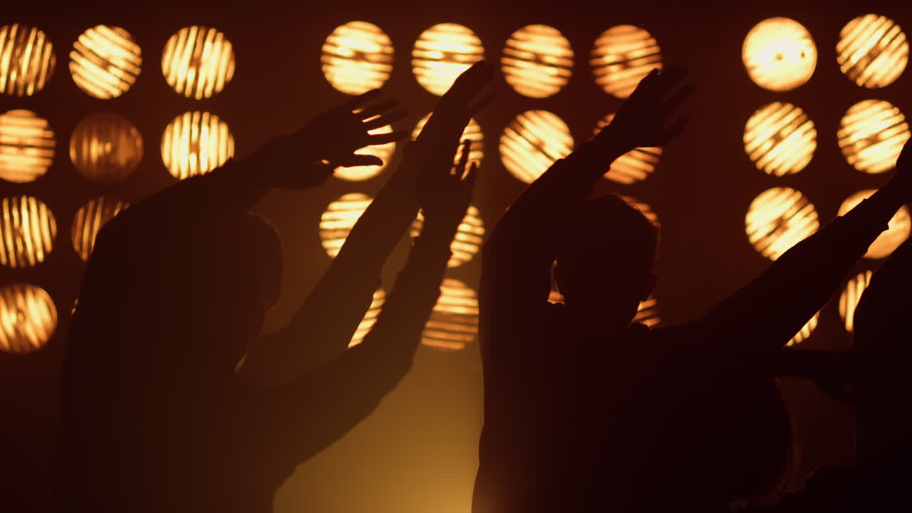 silueta de personas agitando las manos rítmicamente en el concierto. juventud feliz levantando los brazos