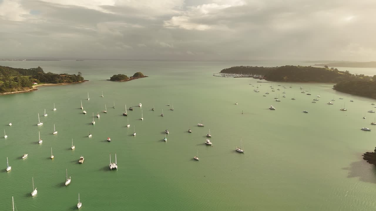 Sailboats moored in turquoise waters off Shelly Beach, Surfdale area, Waiheke Island at sunset, New Zealand