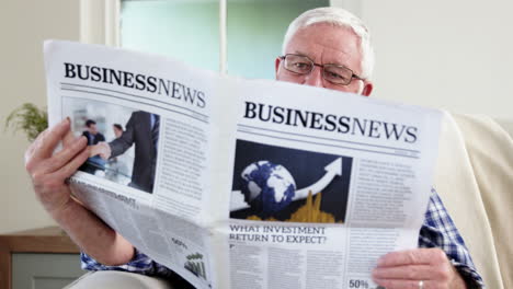 senior man reading newspaper on couch