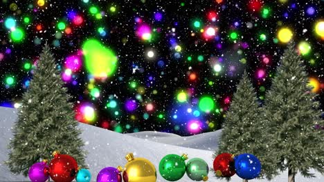 coloridas manchas de luz azul y nieve cayendo sobre coloridas bolas de navidad en el paisaje de invierno