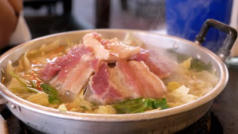 grilling sliced pork and meat on a hot pan asian style with ingredients and sauce