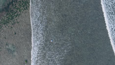 Von-Oben-Nach-Unten-Absteigende-Drohne-über-Totes-Korallenriff-Unter-Flachem-Wasser-Mit-Schwimmendem-Müll-Am-Tropischen-Balangan-Strand-In-Uluwatu,-Bali,-Indonesien