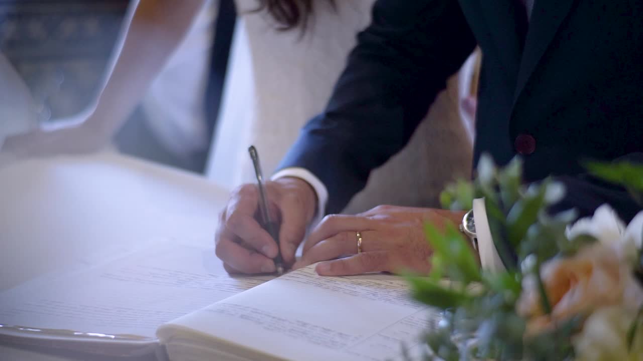 A newly wed groom signing their marriage license, officially legalizing their union